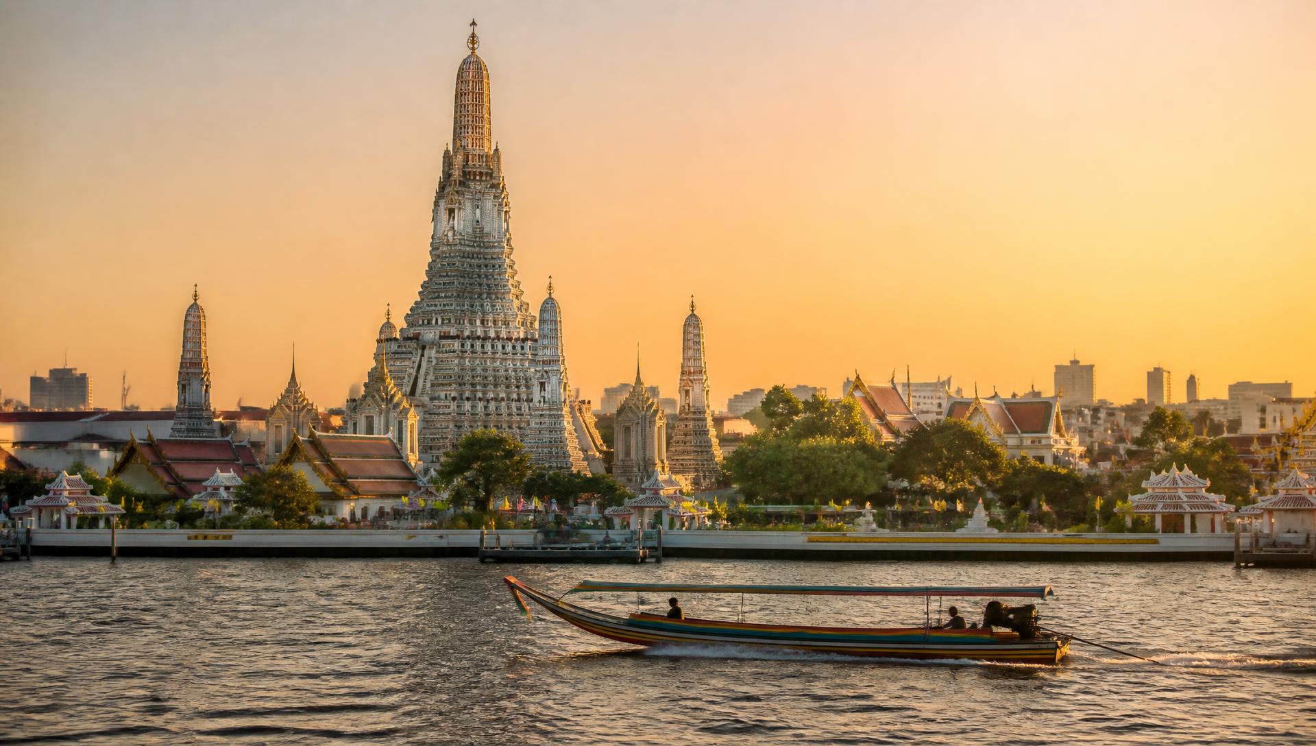 Wat Arun and the Chao Phraya river in Bangkok at golden hour, a long-tail boat crossing the water